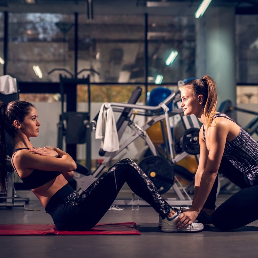 Two women training together on gym mats