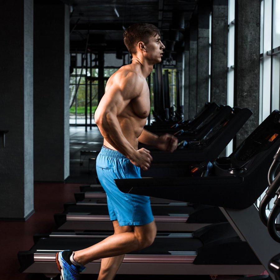 Athlete sprinting on a treadmill in a dark gym
